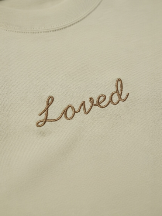 Beige fabric with 'Loved' embroidered in brown thread