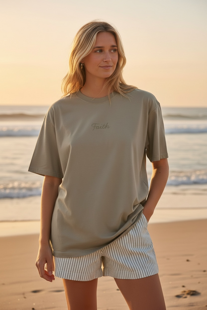Woman standing on a beach wearing a beige t-shirt and striped shorts.