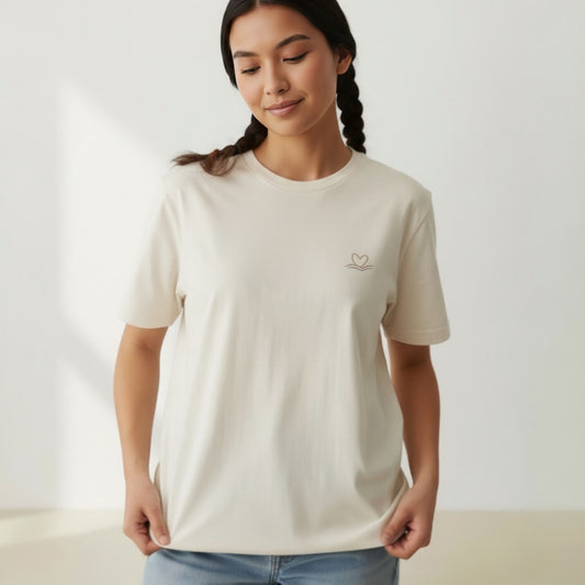 Woman wearing a beige t-shirt with a small logo on a plain background
