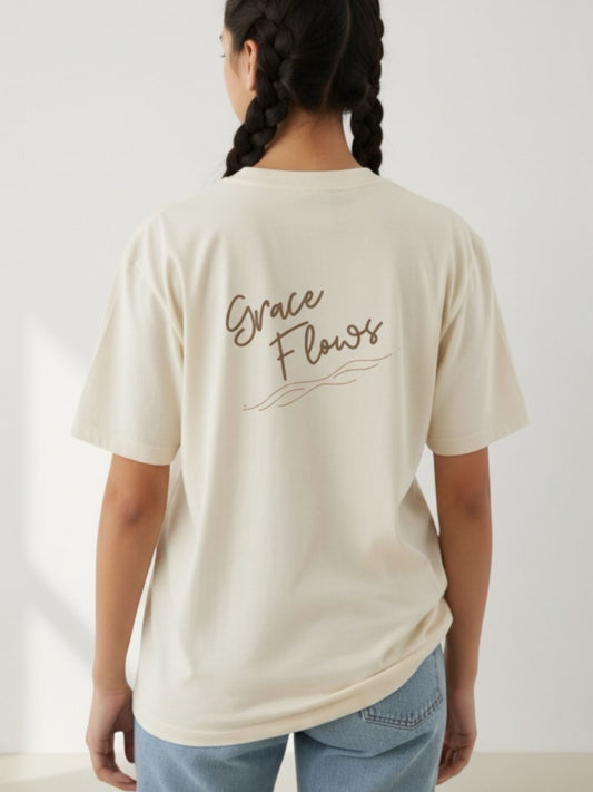 Person wearing a beige t-shirt with 'Grace Flows' text on the back, standing against a plain background.
