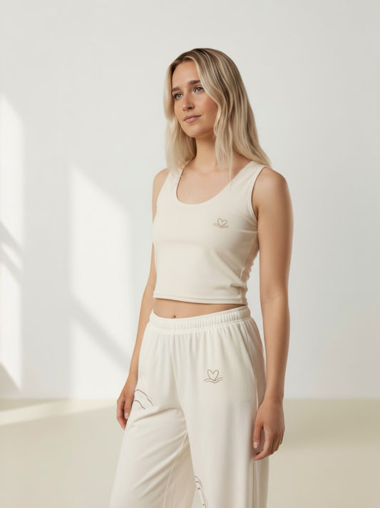 Woman wearing a white tank top and pants with a logo on a light background