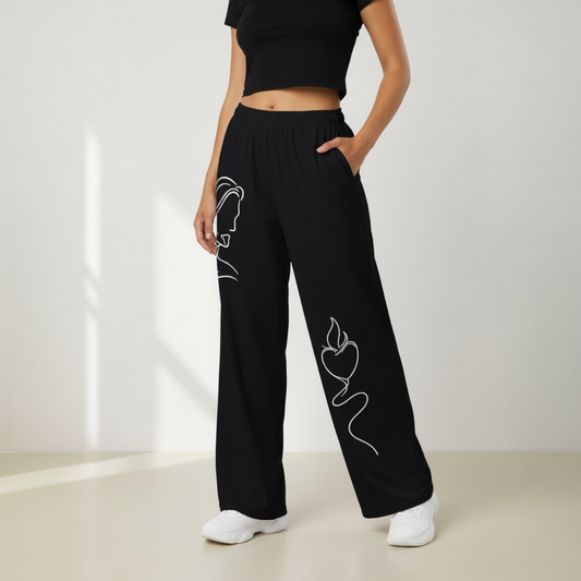 Person wearing black pants with white line art designs on a plain background