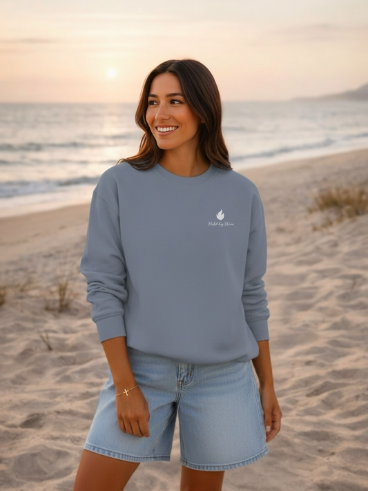 Woman wearing a blue sweatshirt with a logo on a beach at sunset