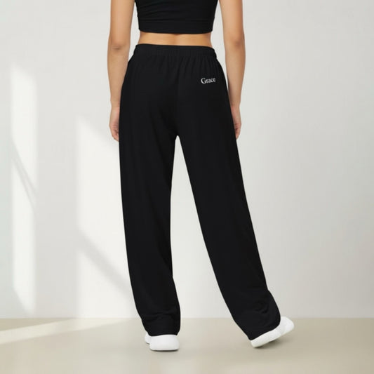 Person wearing black sweatpants with 'Grace' embroidery on a plain background