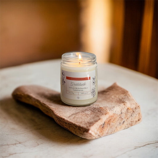 Gratitude Candle – Apple Harvest glowing warmly on a stone base, cozy fall-inspired soy candle by Holy Grace.