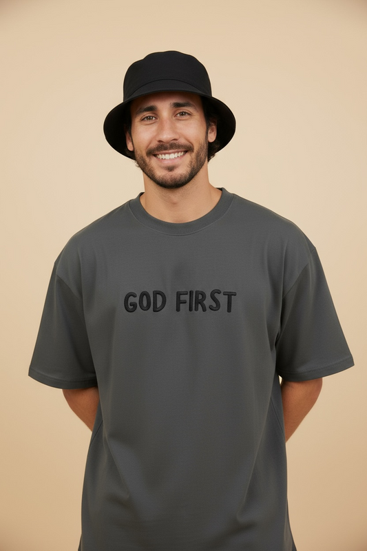 Man modeling the God First oversized Christian t-shirt in a neutral indoor setting.