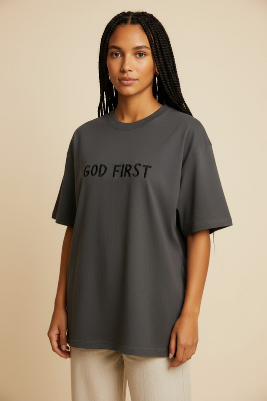 Woman wearing the God First unisex oversized tee in a beige studio, minimalist Christian apparel.
