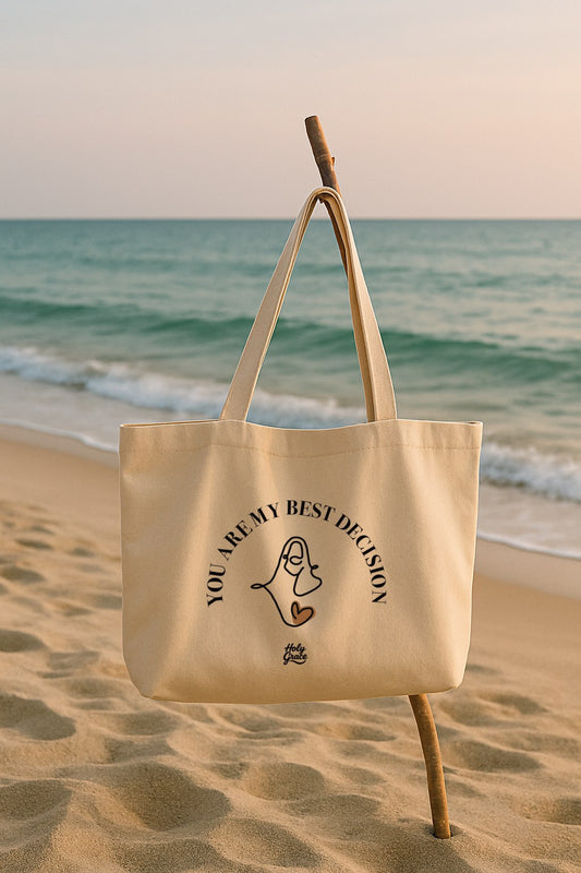 Beige tote bag “You Are My Best Decision” with Jesus face design on the beach by Holy Grace.