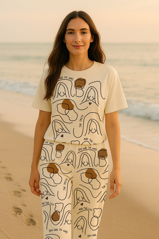 Woman wearing a white t-shirt and pants with abstract designs on a beach.